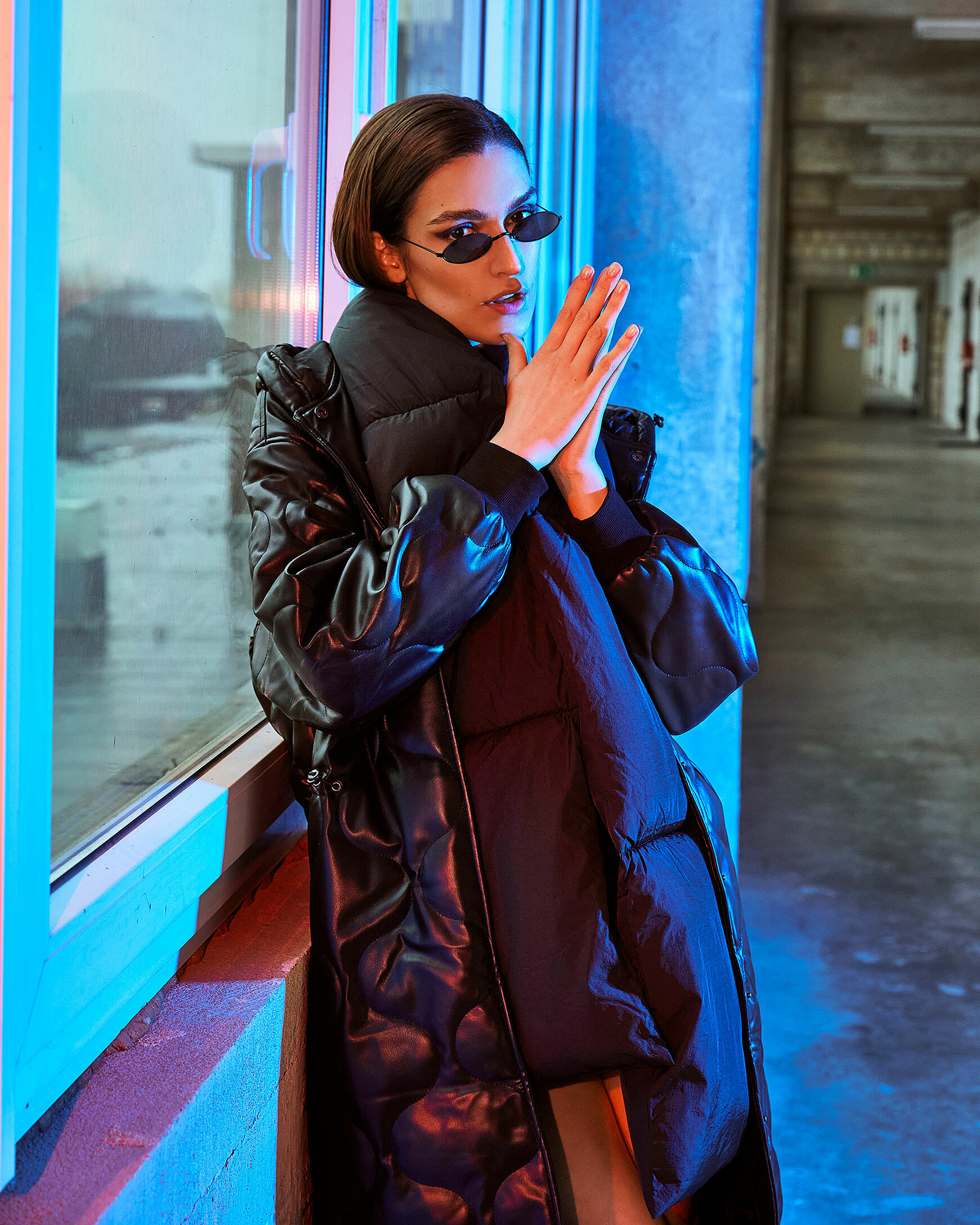 A female model stand in a fabric hall with a winter coat and black glasses