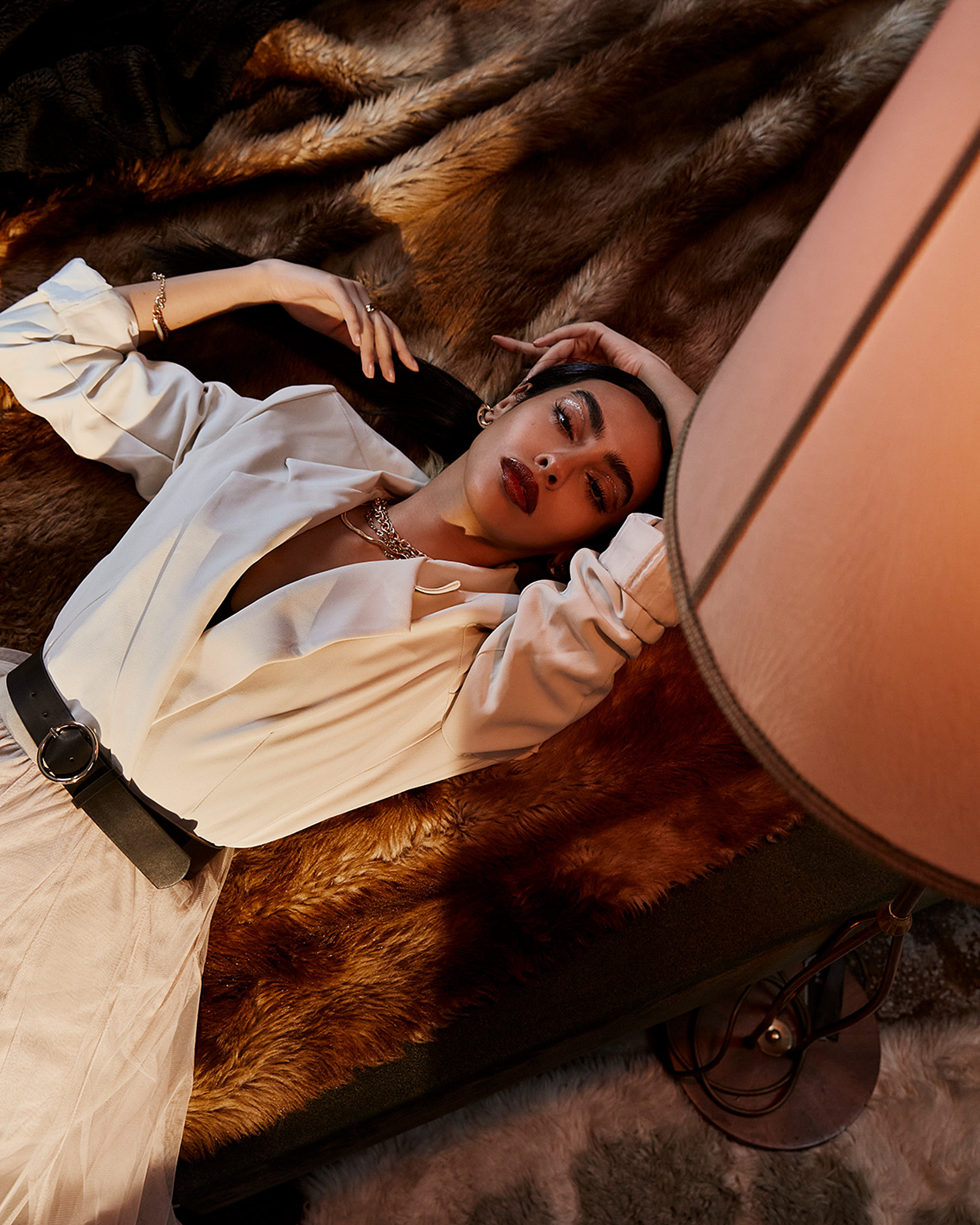 A model lie on the bed in her white blazer and rosa tull skirt with a black belt
