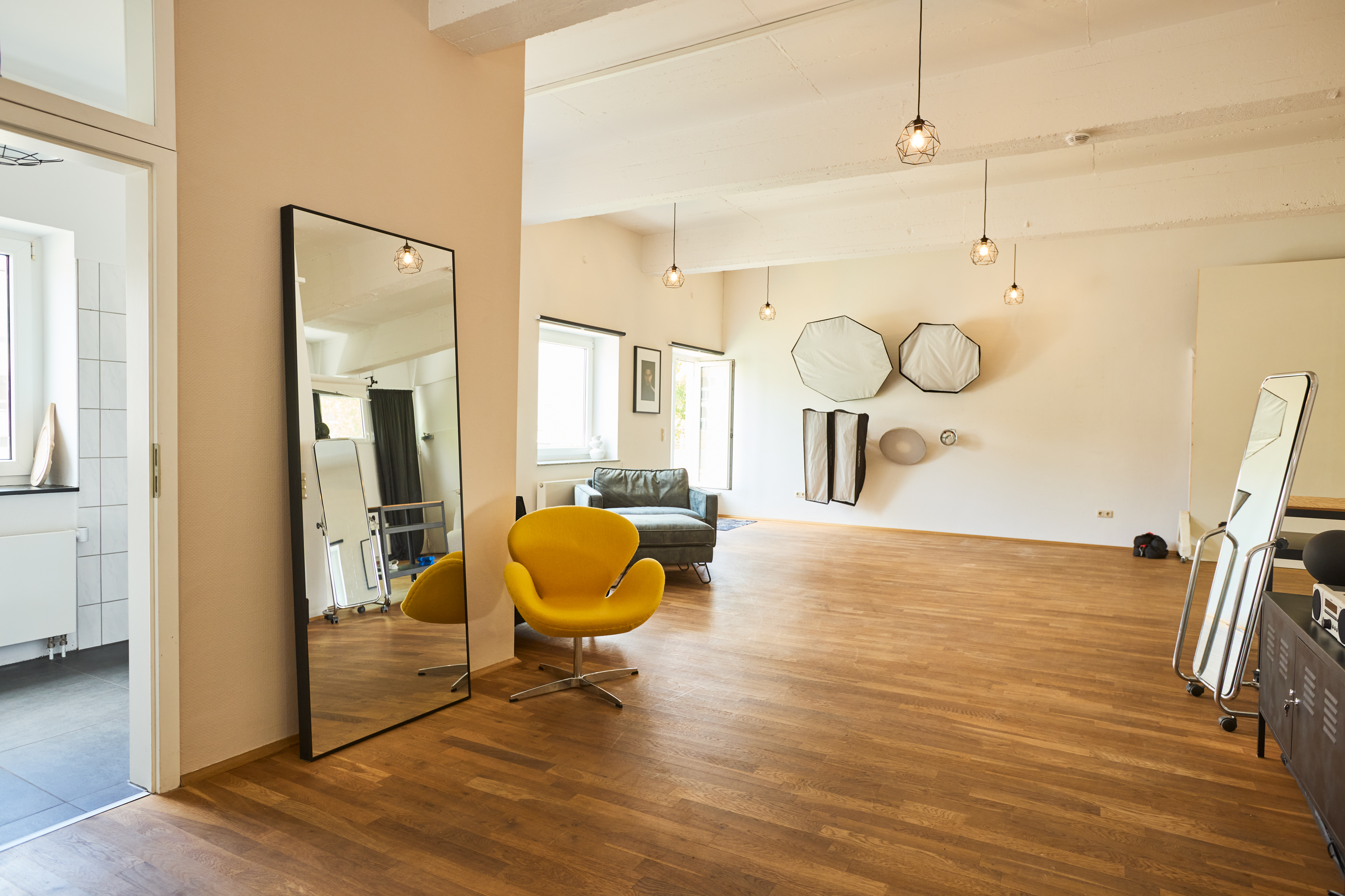 Open studio space with standing mirror, yellow chair and seating