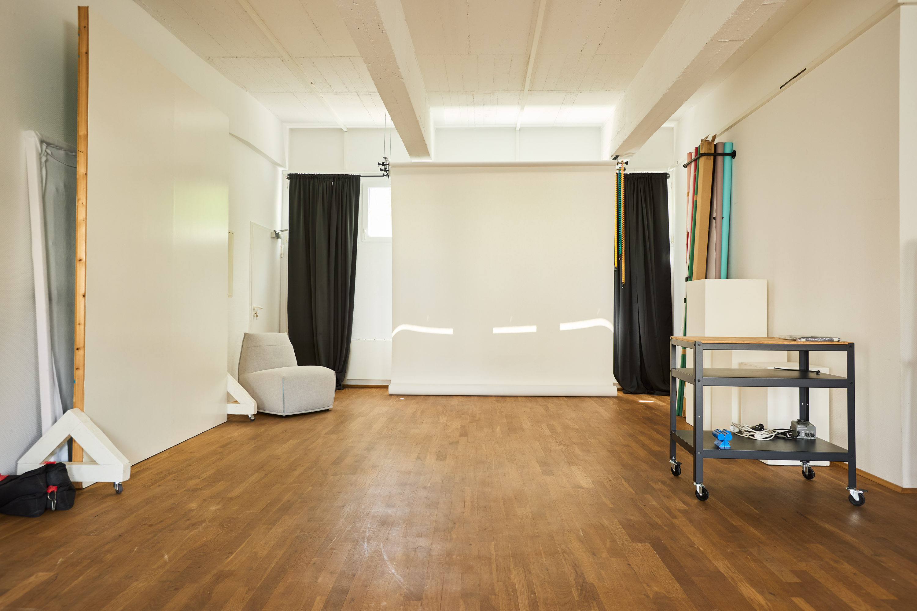 Shooting setup with white backdrop, black side curtains and equipment cart
