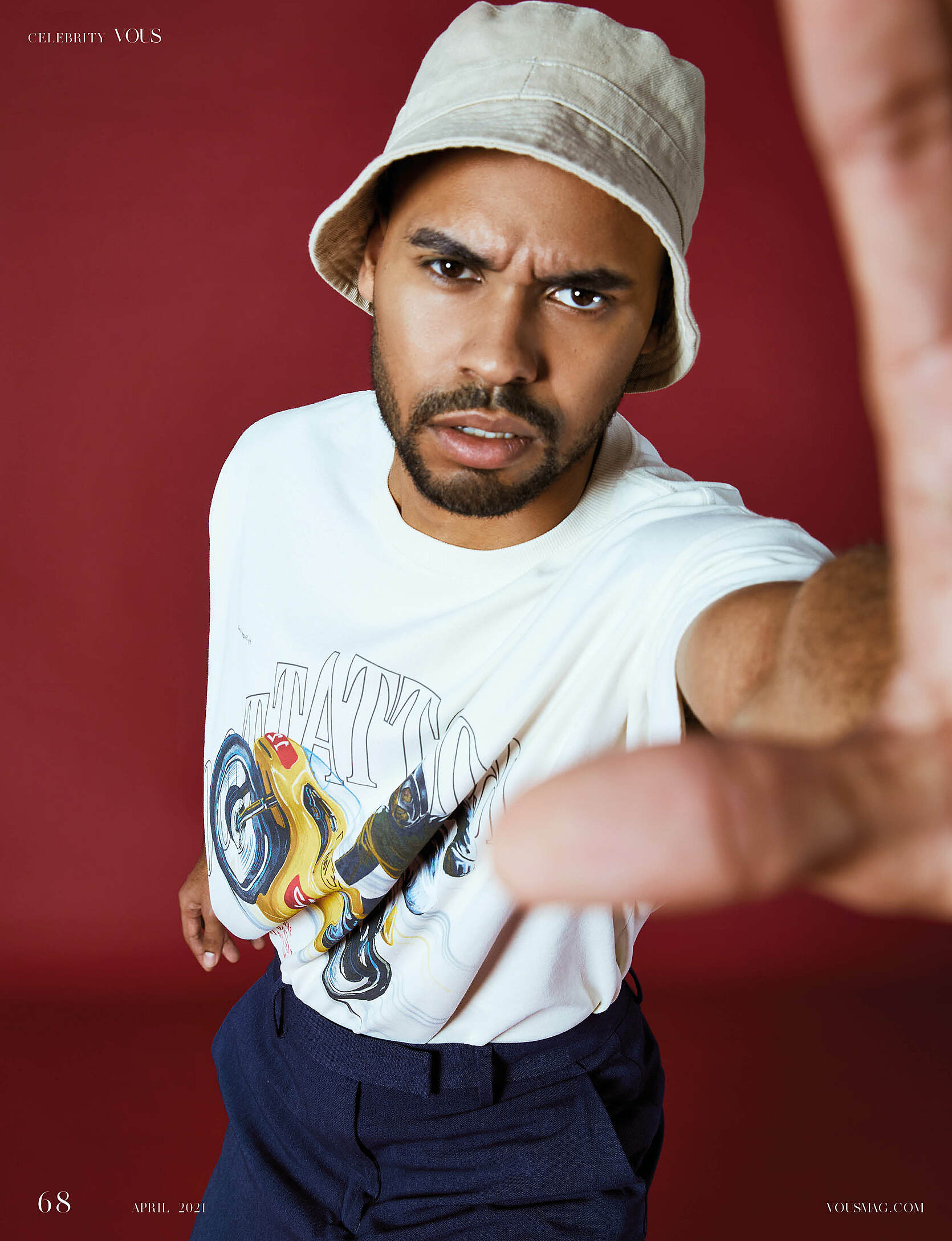 A male model with a white T-shirt, a beige hat and blue trousers