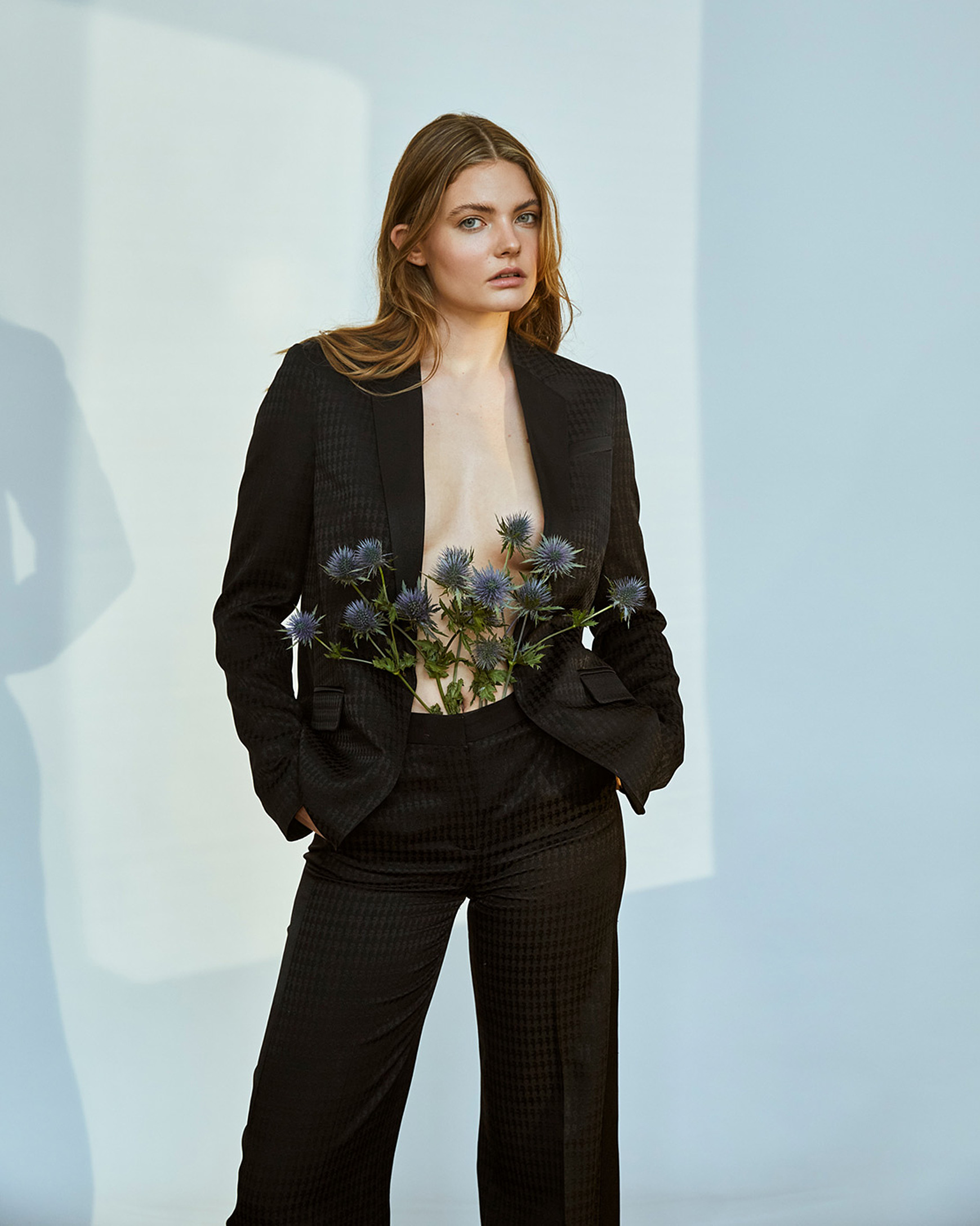A women in a black suit of Karl Lagerfeld and thistles in front of her body
