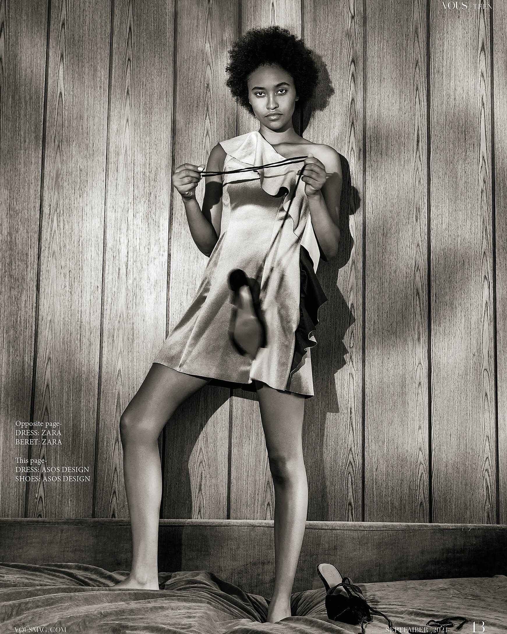 A model stands on the bed with a shoe in her hand