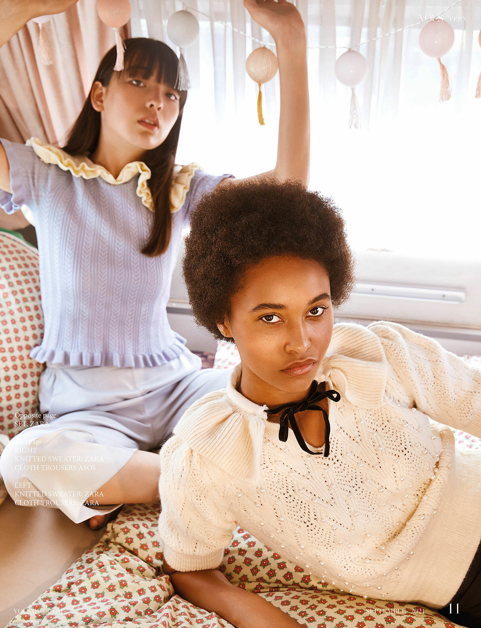 Two models in a camping car sit on the bed and look into the camera