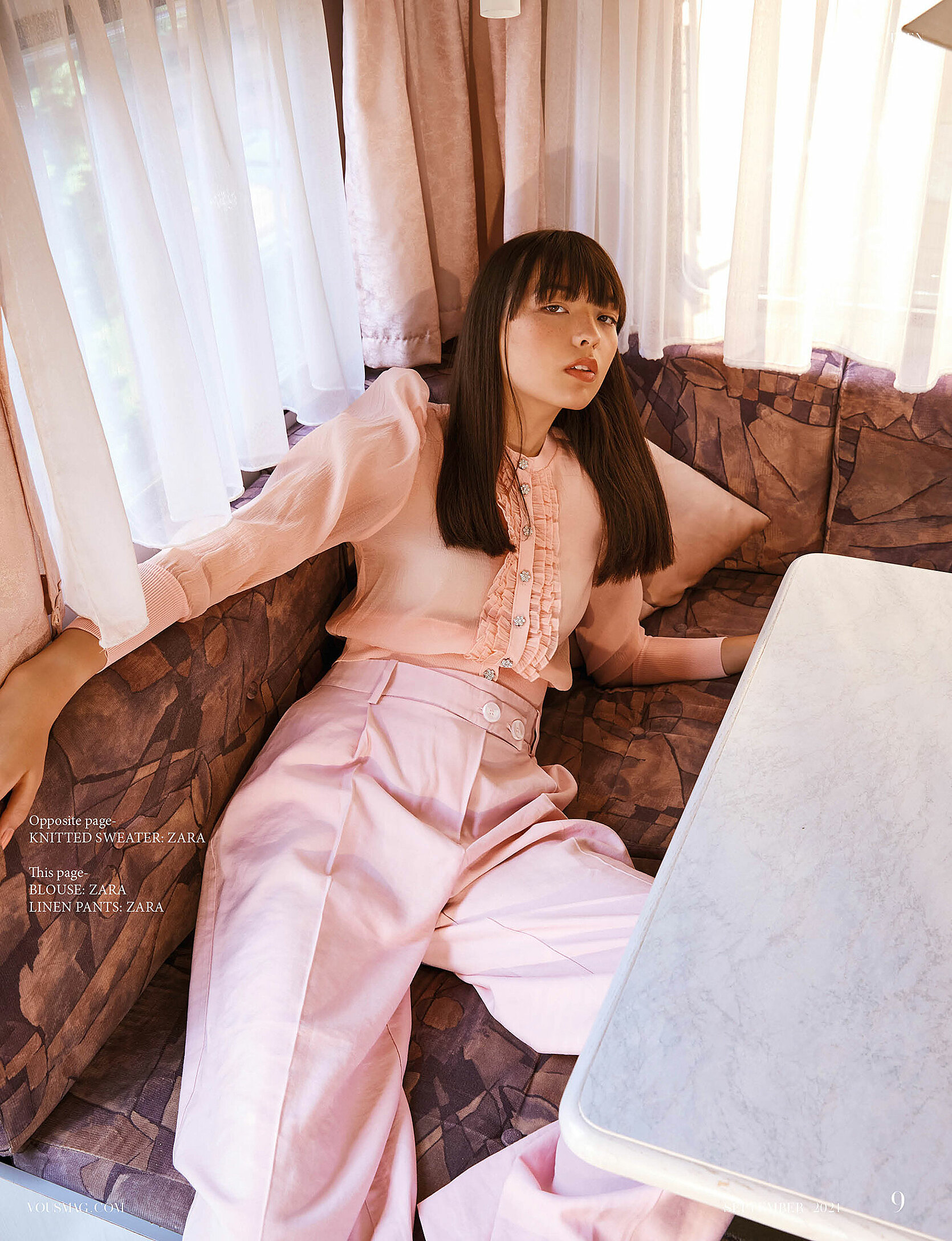 A model in a rose outfit who lie in the dining area in the camping car