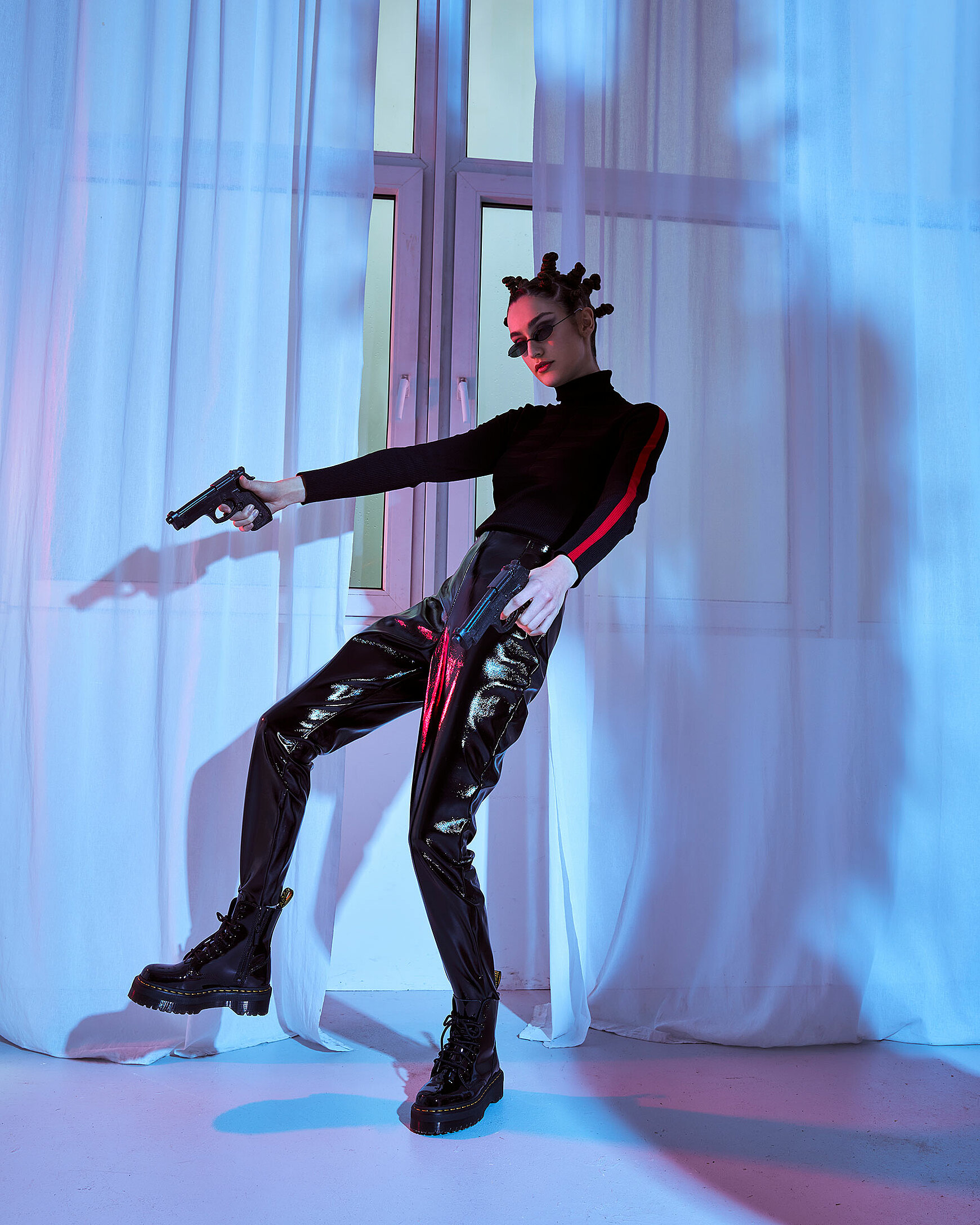 A female model falls in front of windows with pistols in her hand in black clothes