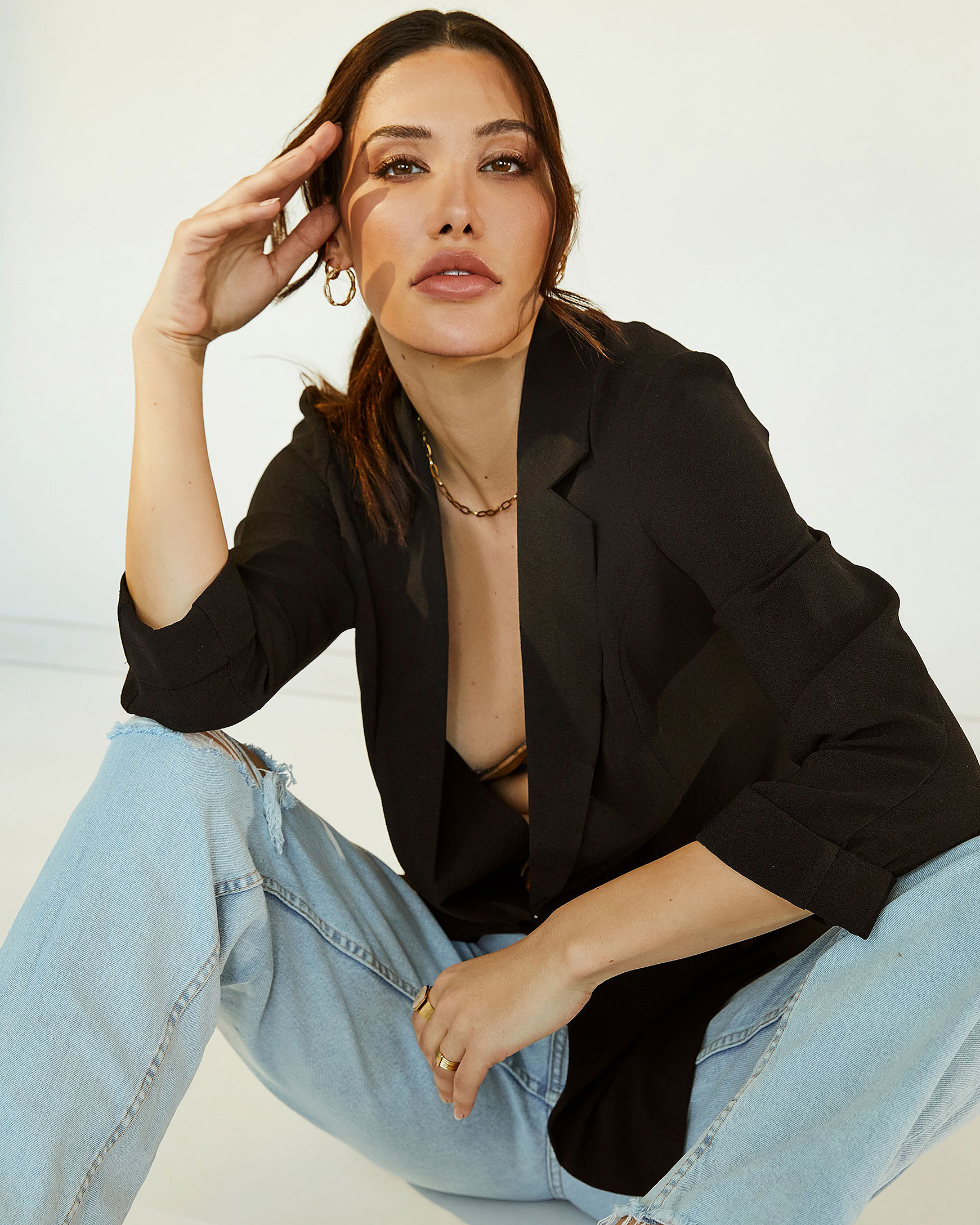 A female model sits on the ground in denim and a black jacket