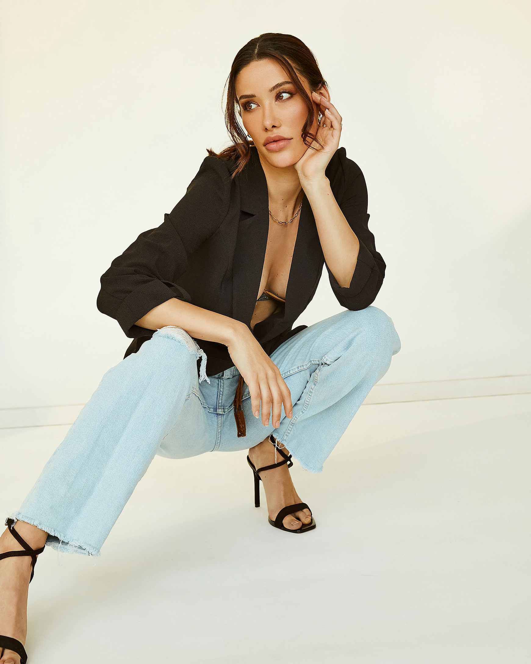 A female model squats in denim and a black jacket