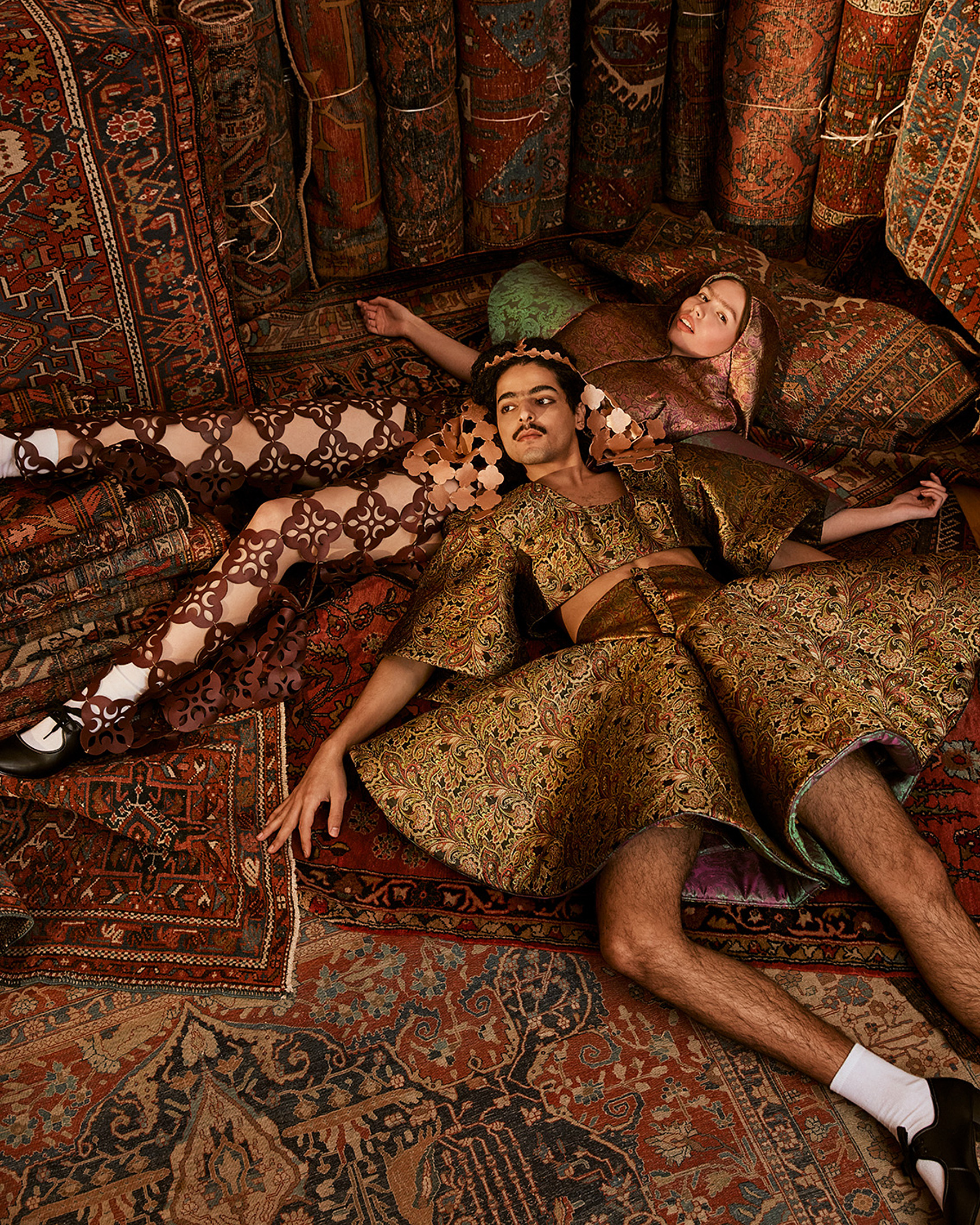 two models lie on the ground surrounded  by carpets 