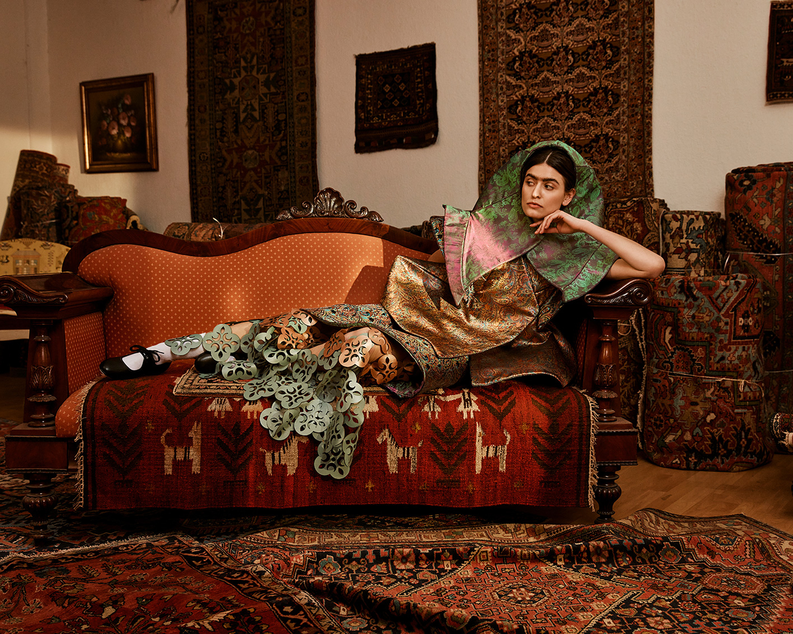 one model lie on a couch surrounded by carpets