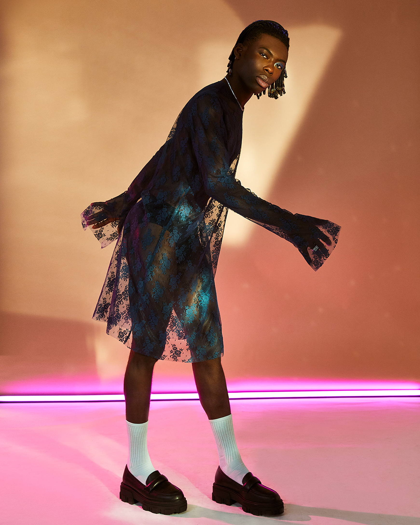 a model in a colorful set with pink light pose in a blue dress