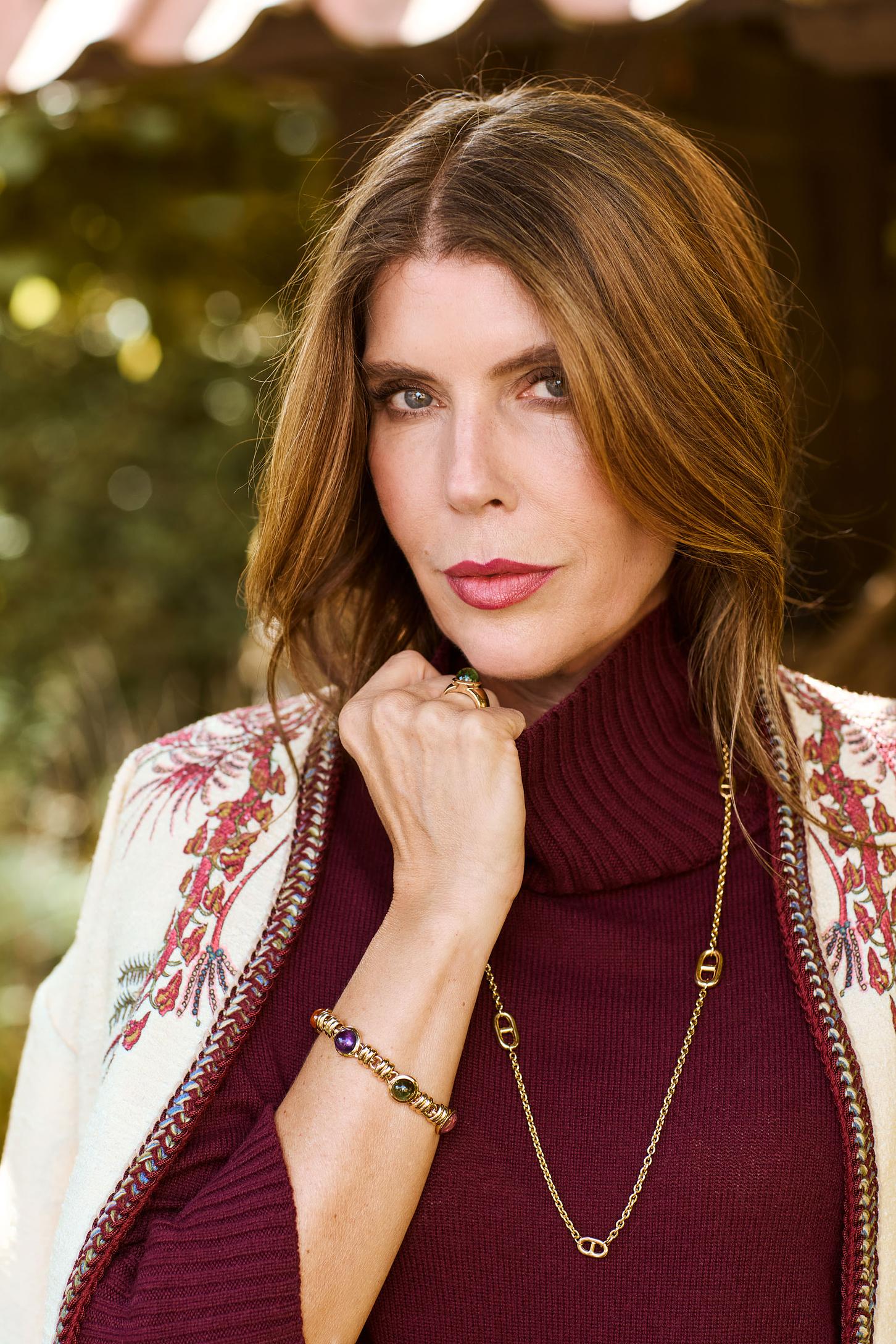 Eine Frau in einem bordeaux roten Pullover posiert mit Schmuck im close up Bereich