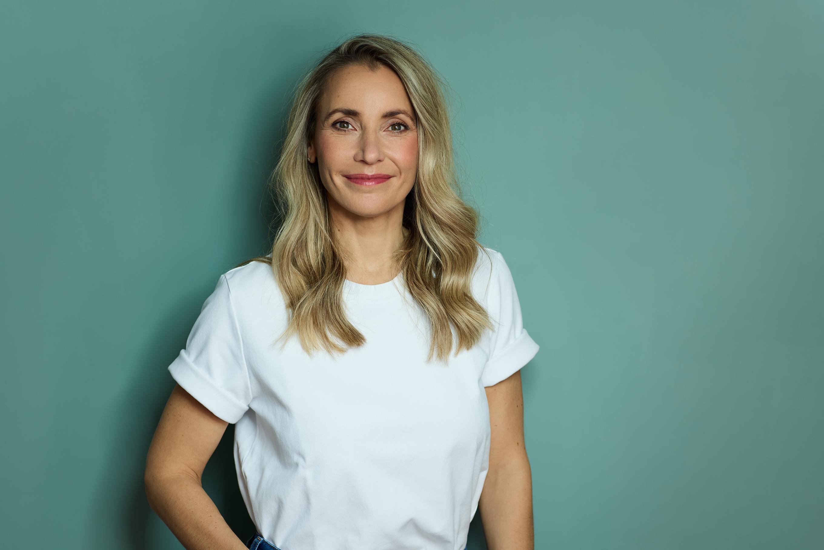 Unternehmerin steht in einem casual T-shirt vor einer mint farbigen Wand